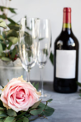 Composition with glass, flowers and bottle of vine on grey concrete background.