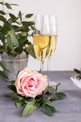 Composition with glasses of vine and flowers on grey concrete background.