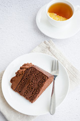 Chocolate Birthday cake. A slice of delicious chocolate cake on a light background. Piece of Cake on a white Plate. Sweet food. Sweet dessert. Vertical orientation. Close up.