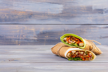 Delicious shawarma sandwich with chicken on wooden background