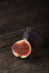Fresh ripe figs. A few figs on an old wooden background. Whole figs and one fig sliced. Fresh fruits, purple figs on the wooden background. Autumn harvest. Free space for text. Free space for text. Da