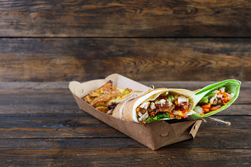Delicious shawarma sandwich with chicken and potato on wooden background