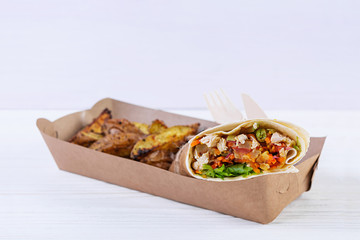 Delicious shawarma sandwich with chicken and potato on wooden background