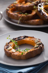 Pumpkin grill served on a plate. Baked pumpkin sliced rings with a knife, fork and napkin on a concrete table. Autumn dish. Halloween dish. Everyday autumn kitchen. Orange colors. space for text.  