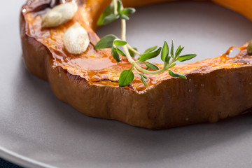 Pumpkin grill served on a plate. Baked pumpkin sliced rings with a knife, fork and napkin on a concrete table. Autumn dish. Halloween dish. Everyday autumn kitchen. Orange colors. space for text.  