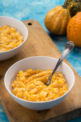 Pumpkin porridge. Homemade pumpkin porridge in a white plate on the table, ready to eat. Pumpkin cream soup or porridge in a bowl Blue table. Family breakfast. Free space for text. View from above.