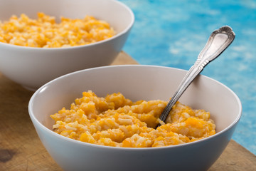 Pumpkin porridge. Homemade pumpkin porridge in a white plate on the table, ready to eat. Pumpkin cream soup or porridge in a bowl Blue table. Family breakfast. Free space for text. View from above.