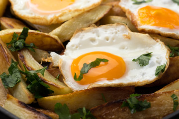 Breakfast in the pan. Fried potatoes with eggs in a skillet. Food bachelor. Cooked by a man. Hot and fresh. Homemade breakfast on black table. Fried eggs and sweet potato hash in cast iron skillet Fre
