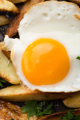 Breakfast in the pan. Fried potatoes with eggs in a skillet. Food bachelor. Cooked by a man. Hot and fresh. Homemade breakfast on black table. Fried eggs and sweet potato hash in cast iron skillet Fre