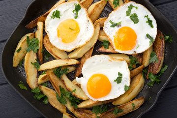 Breakfast in the pan. Fried potatoes with eggs in a skillet. Food bachelor. Cooked by a man. Hot and fresh. Homemade breakfast on black table. Fried eggs and sweet potato hash in cast iron skillet Fre