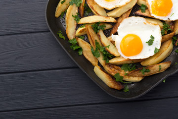 Breakfast in the pan. Fried potatoes with eggs in a skillet. Food bachelor. Cooked by a man. Hot and fresh. Homemade breakfast on black table. Fried eggs and sweet potato hash in cast iron skillet Fre