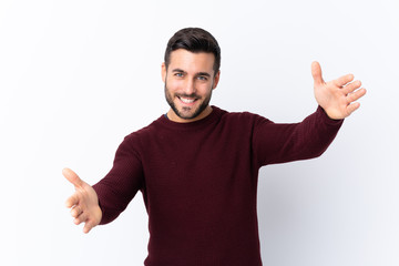 Fototapeta premium Young handsome man with beard over isolated white background presenting and inviting to come with hand