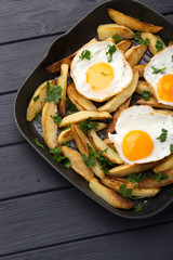 Breakfast in the pan. Fried potatoes with eggs in a skillet. Food bachelor. Cooked by a man. Hot and fresh. Homemade breakfast on black table. Fried eggs and sweet potato hash in cast iron skillet Fre