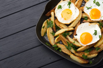 Breakfast in the pan. Fried potatoes with eggs in a skillet. Food bachelor. Cooked by a man. Hot...