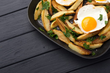 Breakfast in the pan. Fried potatoes with eggs in a skillet. Food bachelor. Cooked by a man. Hot and fresh. Homemade breakfast on black table. Fried eggs and sweet potato hash in cast iron skillet Fre