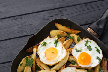Breakfast in the pan. Fried potatoes with eggs in a skillet. Food bachelor. Cooked by a man. Hot and fresh. Homemade breakfast on black table. Fried eggs and sweet potato hash in cast iron skillet Fre