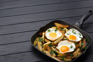 Breakfast in the pan. Fried potatoes with eggs in a skillet. Food bachelor. Cooked by a man. Hot and fresh. Homemade breakfast on black table. Fried eggs and sweet potato hash in cast iron skillet Fre
