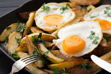 Breakfast in the pan. Fried potatoes with eggs in a skillet. Food bachelor. Cooked by a man. Hot and fresh. Homemade breakfast on black table. Fried eggs and sweet potato hash in cast iron skillet Fre