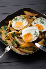 Breakfast in the pan. Fried potatoes with eggs in a skillet. Food bachelor. Cooked by a man. Hot and fresh. Homemade breakfast on black table. Fried eggs and sweet potato hash in cast iron skillet Fre