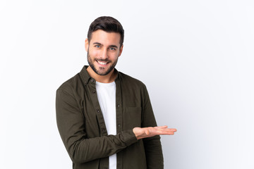 Young handsome man with beard over isolated white background presenting an idea while looking smiling towards