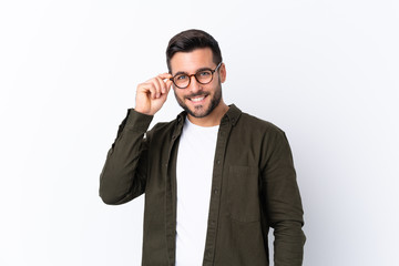 Young handsome man with beard over isolated white background with glasses and happy