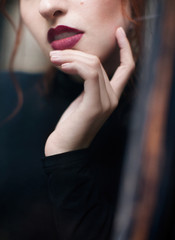 Portrait of a red-haired girl in a black turtleneck and trousers with professional makeup from a stylist. A shot near a vintage window.