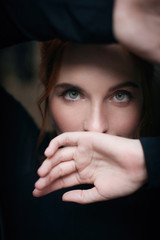 Portrait of a red-haired girl with green eyes in a black turtleneck with a mysterious witching look. A shot near a vintage window.