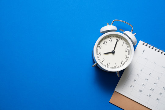 close up of calendar and alarm clock on the blue table background, planning for business meeting or travel planning concept