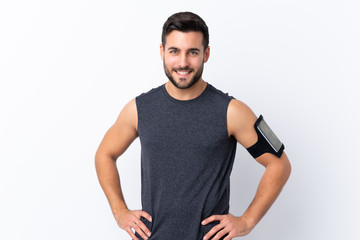 Young sport handsome man with beard over isolated white background posing with arms at hip and smiling