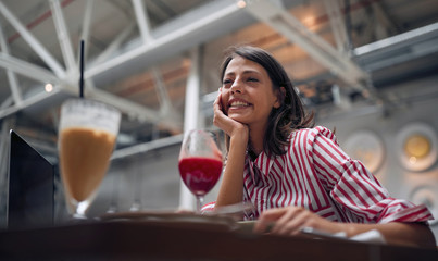 Smiling woman sitting at cafe having fun, laughing.
