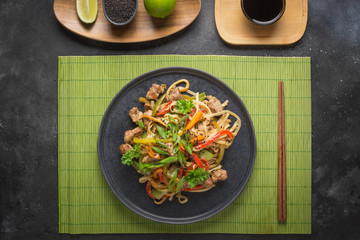 Udon stir-fry noodles with pork on green mat. Asian cuisine.