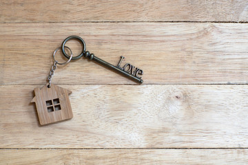 House key in heart shape with home keyring on white wood background