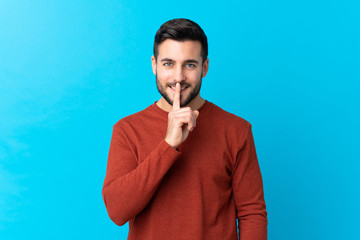 Young handsome man with beard over isolated blue background doing silence gesture