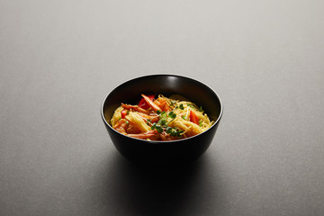 noodles with shrimps and vegetables in bowl on black background