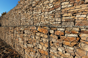 A drainage wall strengthens and holds an earthen slope. It consists of natural stones laid in a metal mesh.