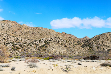 a desert mountain and dry river with a blue sky