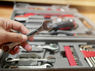 Fototapeta premium A man's hand is holding a wrench in various sizes in a toolbox.