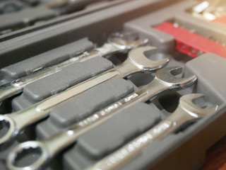 A man's hand is holding a wrench in various sizes in a toolbox.