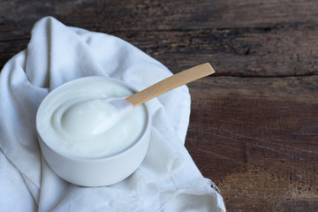 Natural homemade plain organic yogurt in wood bowl on wood texture background