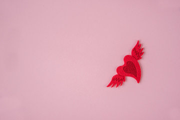 Red winged heart on a pink background