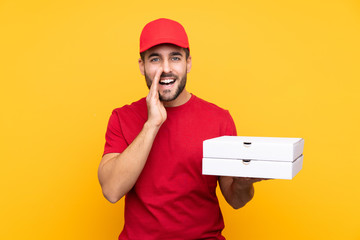 pizza delivery man with work uniform picking up pizza boxes over isolated yellow background...