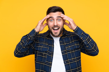 Young handsome man with beard over isolated yellow background with surprise expression