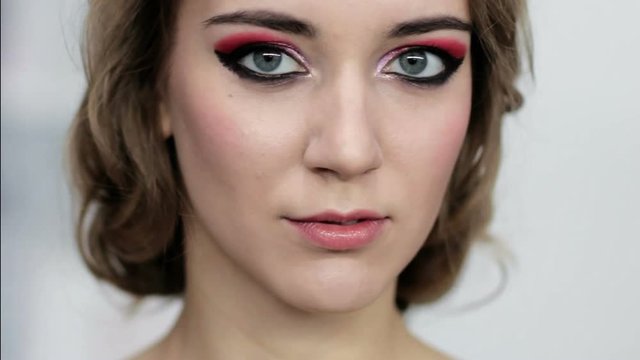 Makeup art. Female beauty. Portrait of woman with red eyeshadow nude lip gloss wavy hairstyle.