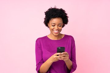 African american woman over isolated pink background sending a message with the mobile