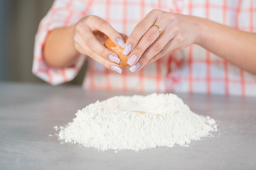 Woman adding an egg to a flour mound