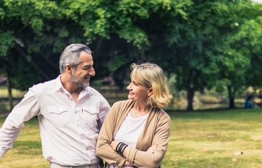 Obraz premium Lovely senior elderly smiling couple man and woman look at each other in romantic moment in the park. Warm heart marriage and lover bonding and relationship. Husband and wife in love photo concept