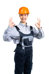 Smiling construction woman wearing protect helmet and overall showing OK gesture. Isolated