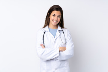 Fototapeta premium Teenager girl over isolated white background wearing a doctor gown and with arms crossed