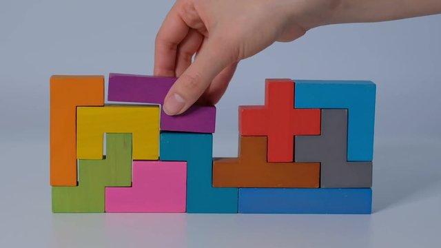 concept of children's education. Closeup Slow motion. Hand holding piece of wooden block puzzle. wood cube stacking. Concept of complex and smart logical thinking.