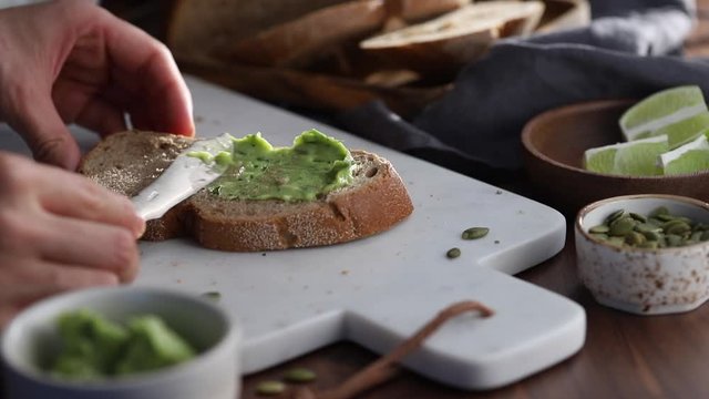 Spreading guacamole on a rye bread toast. Healthy eating concept